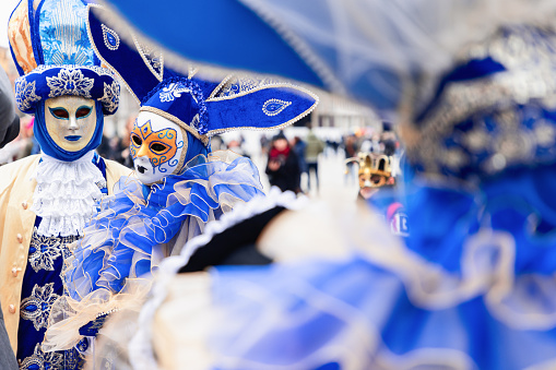 Venice - Italy. February 5, 2023: Participants of the Venetian carnival in original masks in blue colors on Piazza San Marco