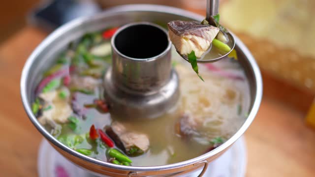 Close up of hot pot spicy Tom Yum soup boiling traditional Thai Food.