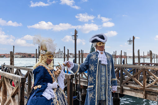 Venice - Italy. February 5, 2023: Couple in elegant baroque costumes for the Venice Carnival on the embankment