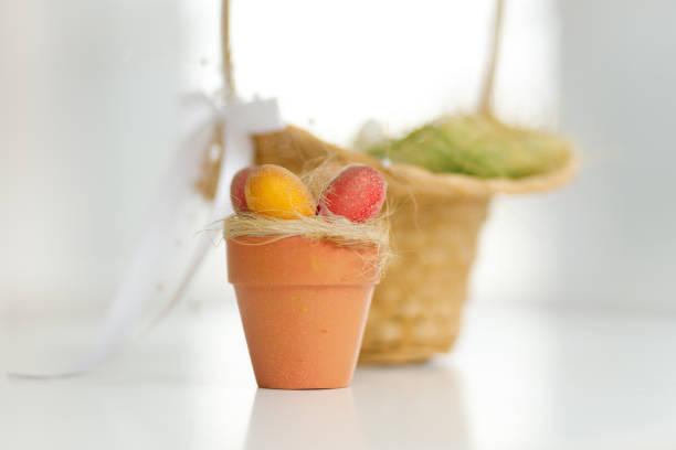 Easter eggs in a basket. Chicken eggs, twigs with green leaves on the hay. Easter holiday concept background. Copy space, white background.