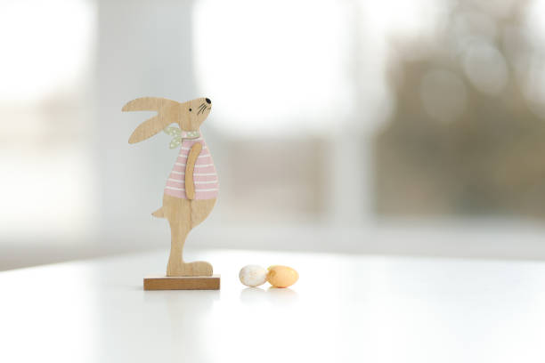 Wooden Easter bunny and decorative eggs. Blurred background, copy space