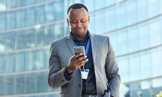 African american businessman using smartphone browsing online messages texting on mobile phone in city