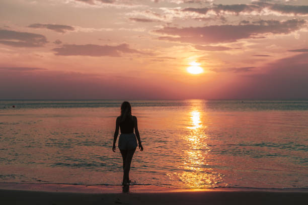 istock Woman walking on a beach during sunset 1471606788