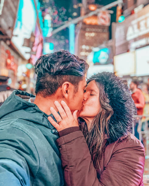 Couple taking selfie at time square on New Year's Eve Shot at night, happy people traveling in the famous city taking photos at different locations. times square new years eve stock pictures, royalty-free photos & images