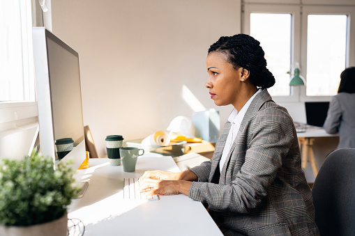 Side-view of African-American businesswoman working on laptop in the modern office