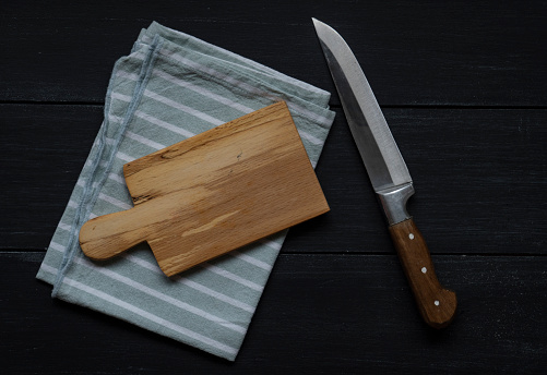 chopping board with knife and napkin on wooden table