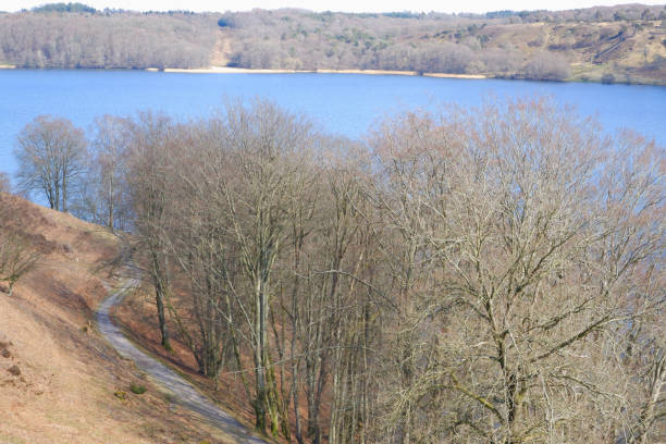 Landscape in early spring. A beautiful lake surrounded by hills with trees without leaves. Early spring. Spring landscape with trees by the river