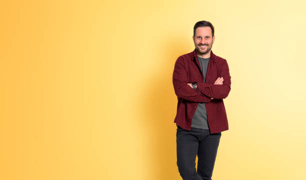 istock Smiling man in maroon shirt standing against yellow background. 1471614874