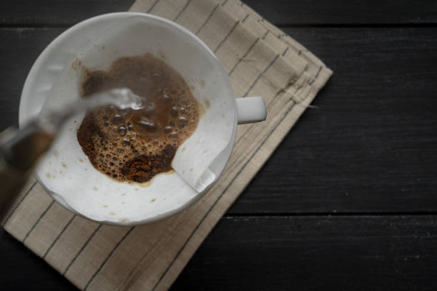 istock Brewed coffee, pouring hot water on ground coffee in a filter on a mug for a stimulating drink, rustic wooden table 1471615911