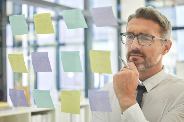 istock Business, man and thinking with sticky note for planning innovative corporate ideas with vision. Plan, idea and businessman brainstorming a company strategy using post it for schedule or calendar 1471615996