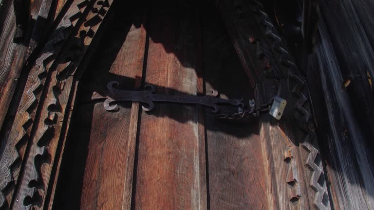 Chain and metal  lock  on the gates of an old wooden house, swaying in the wind, bees fly above them on a sunny summer day.