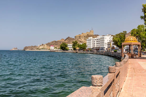 vista del lungomare di mutrah, mutrah souq dall'esterno e mutrah corniche con la vista sullo sfondo del forte mutrah e del monumento riyam, gigantesco monumento bianco, a mutrah, muscat, oman, medio oriente. - oman greater masqat fort tourism foto e immagini stock