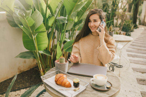 istock Young woman drinking fresh cappuccino with croissant, using her smartphone. 1471617086