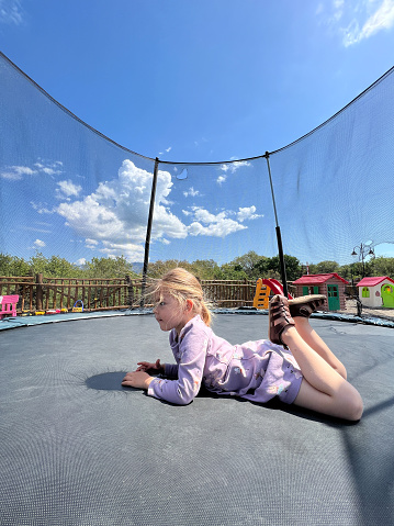 Little girl lying on her stomach on a trampoline. High quality photo