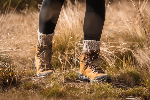 Hiking boot. Walk on trekking trail in grass. Leather ankle boots and knitted alpaca socks