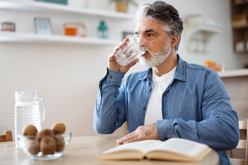 Mature man drinking a glass of water at home