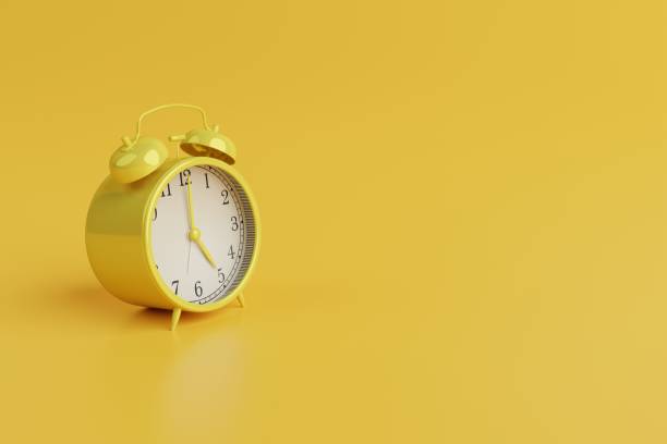 istock Yellow retro alarm clock on yellow background. 1471628090