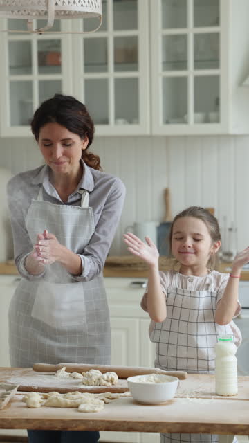 Mom and daughter having fun in kitchen while making dough