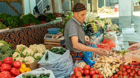 Osh, Kyrgyzstan - May 2022: At Osh market, a local trader sells fresh fruits and vegetables from a stand.