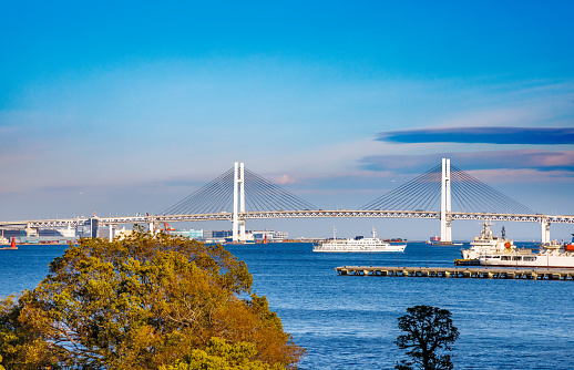A large bridge over Yokohama Port and a pleasure boat sailing on the sea