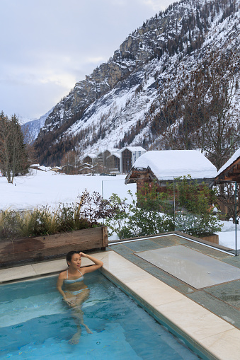 Woman relaxing in hot water SPA pool in Courmayeur among snowy alps, Valle d'Aosta