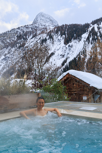 Woman relaxing in hot water SPA pool in Courmayeur among snowy alps, Valle d'Aosta