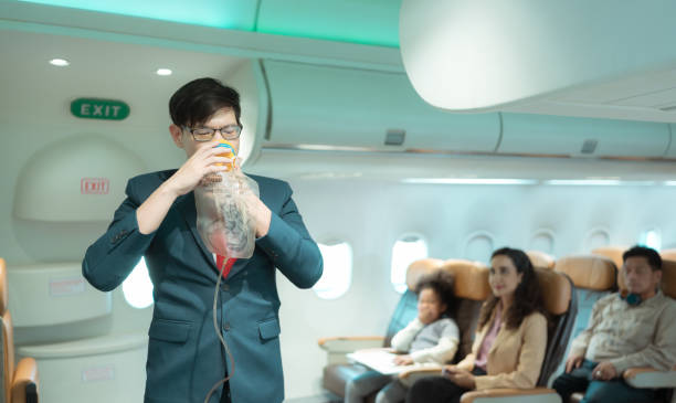 Flight attendants show how to use safety devices and recommend emergency exits. Flight attendants show how to use safety devices and recommend emergency exits. oxygen mask plane stock pictures, royalty-free photos & images