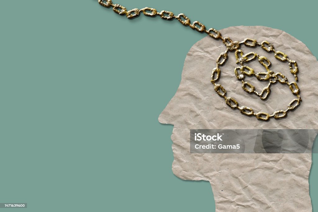 Dogmatism regarding mental health, copy space background. Dogmatism concerning mental health, concept. Man head in chains on green background with copy space. Mental Health Stock Photo