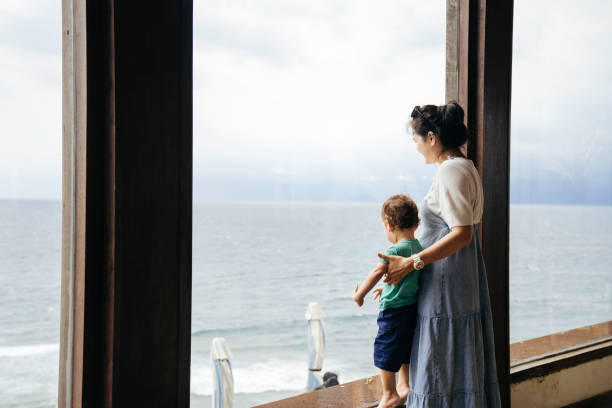 istock asian woman carrying her child looking thorough on window 1471643393