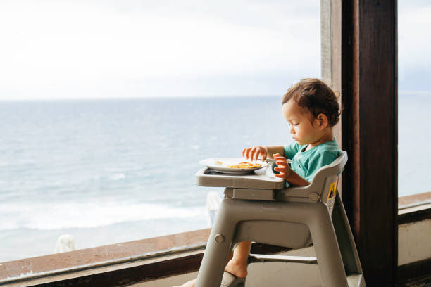 istock baby eating pizza with beach at the view 1471643526
