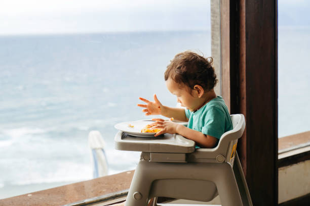 istock baby eating pizza with beach at the view 1471643542