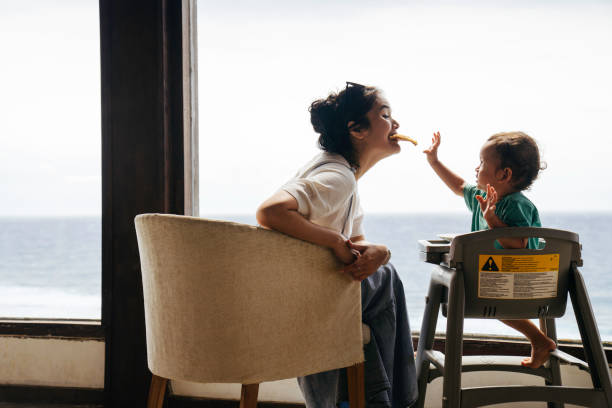 femme asiatique avec son fils assis sur la chaise en train de manger une pizza - portrait babies and children people nature photos et images de collection