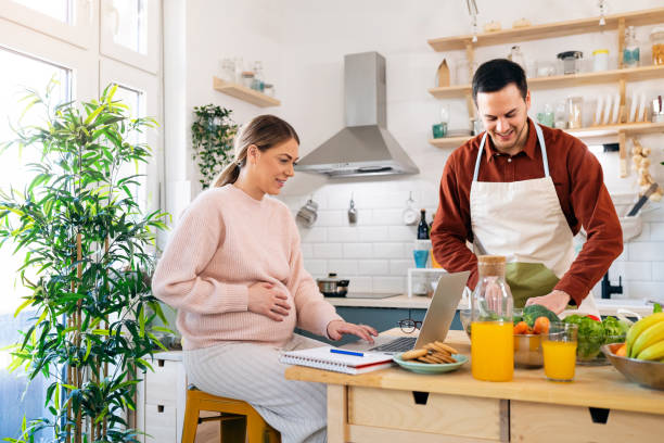 istock Pregnant woman working on laptop while her husband making healthy breakfast for them 1471644278