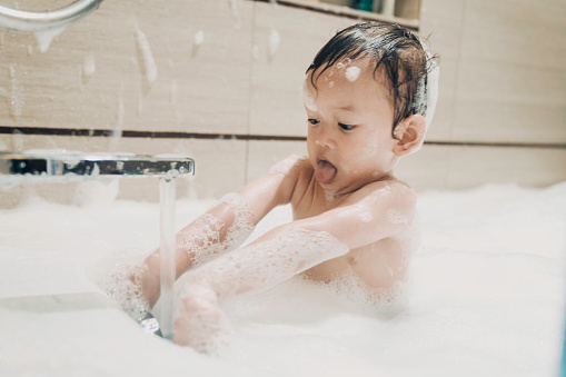 A male toddler is taking a bath in a bathu