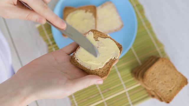 A person's hands delicately spreading butter on a piece of freshly sliced bread,