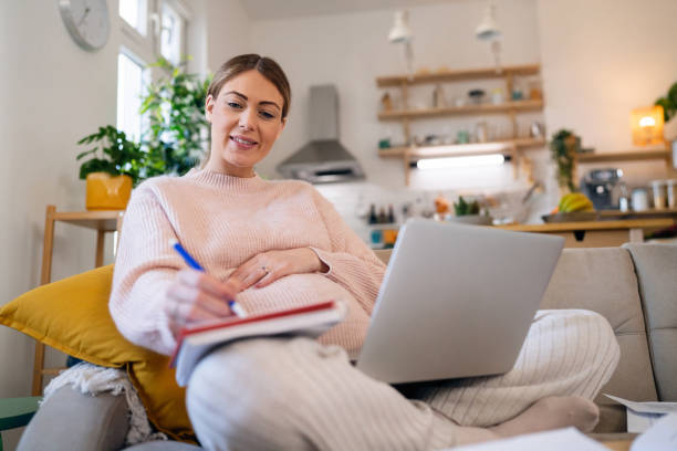 istock Pregnant woman working on laptop while organizing home finances 1471646722