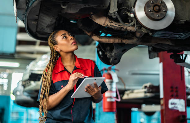 istock Engineer team checking under car condition on lifter in garage.Young auto mechanic in uniform is looking at camera and smiling examining car. 1471646954