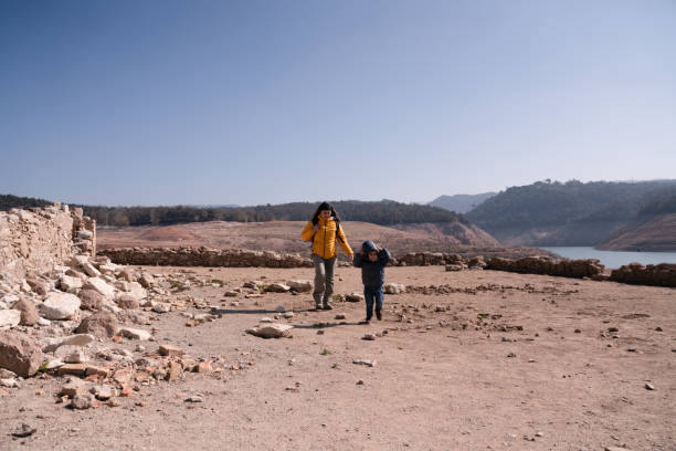 A heartwarming scene of a parent and child enjoying a leisurely stroll through nature.  The sunlit field offers a peaceful backdrop to their bonding moment.