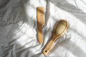 Wooden hairbrushes on white bed background with shadows from window