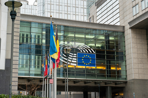 Brussels, Belgium – February 21, 2022: European Parliament building with EU flag and European nations flags blowing in the wind.