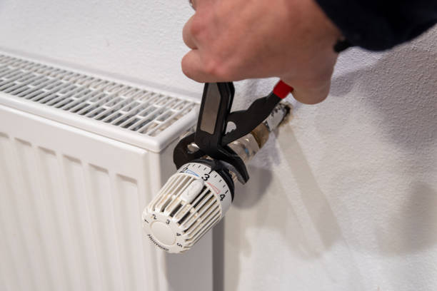 istock Hand with water pipe pliers on radiator thermostat 1471655810