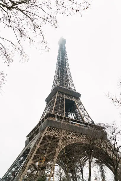 Low angle view of the Eiffel tower in Paris, France on cold and foggy winter morning.