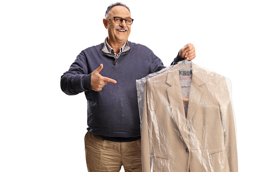 Mature man holding suit from dry cleaners and pointing isolated on a white background