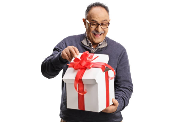 Happy mature man opening a gift box with red ribbon stock photo