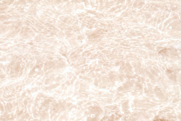 A thin layer of clear water over the sand. A seaside or ecology-themed background with clear sea water over a sandy bottom.