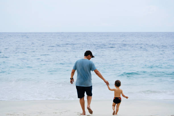 istock asian man teaching his baby walking on the beach 1471659502