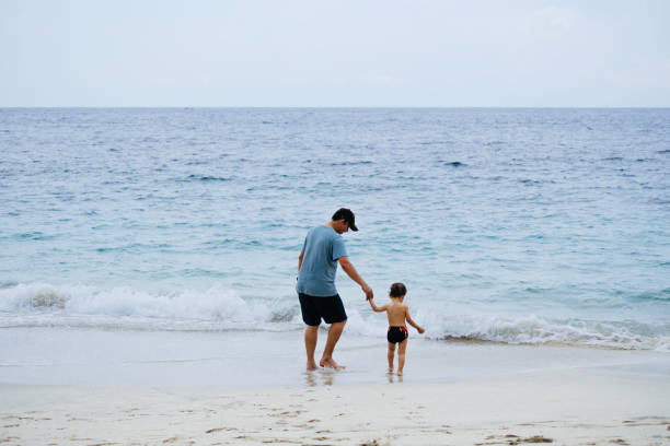 istock asian man teaching his baby walking on the beach 1471659504