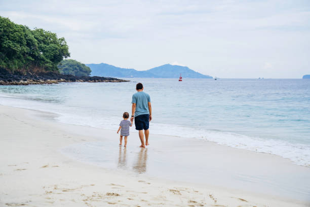 istock asian man teaching his baby walking on the beach 1471659567