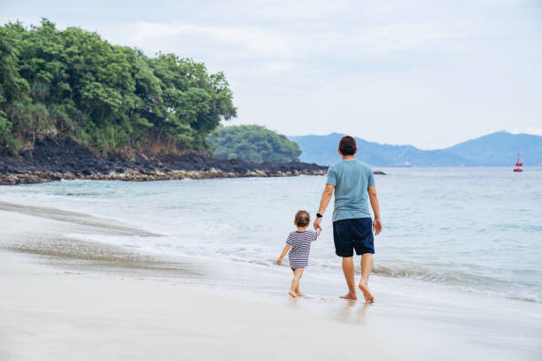 istock asian man teaching his baby walking on the beach 1471659595