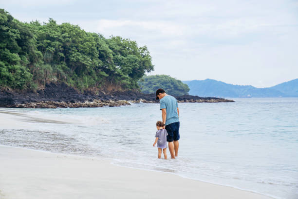 istock asian man teaching his baby walking on the beach 1471659596